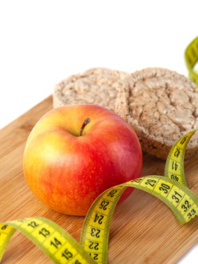 Beyaz arka planda ölçü bandı ile elma, turuncu, kivi