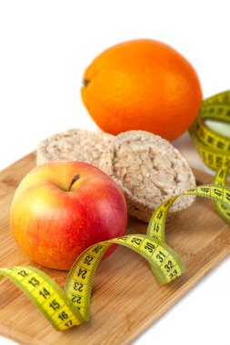 Beyaz arka planda ölçü bandı ile elma, turuncu, kivi