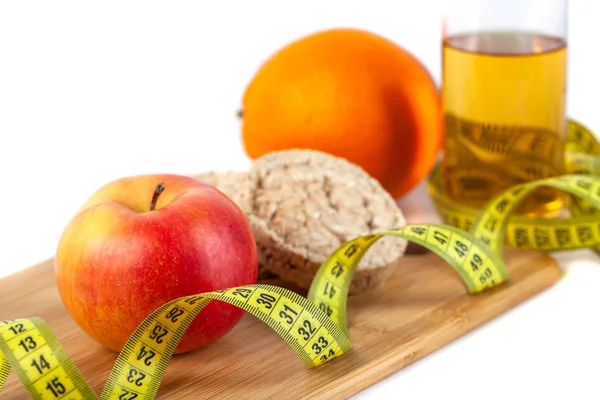 Beyaz arka planda ölçü bandı ile elma, turuncu, kivi