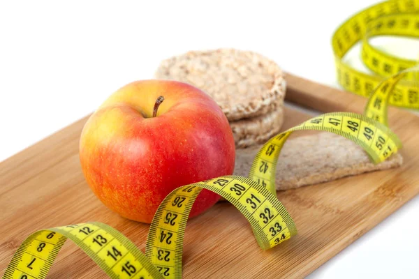 Beyaz arka planda ölçü bandı ile elma, turuncu, kivi