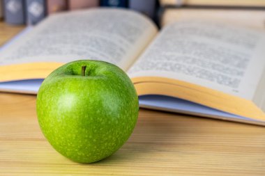 ahşap masada kitap ve yeşil elma