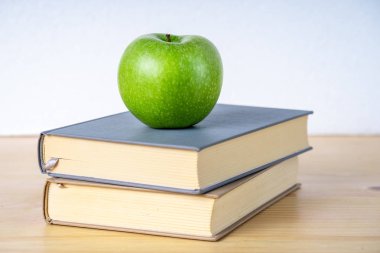 Ahşap masada iki kitap ve yeşil elma