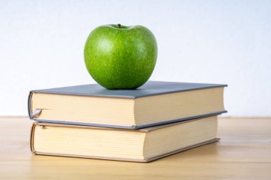 Ahşap masada iki kitap ve yeşil elma