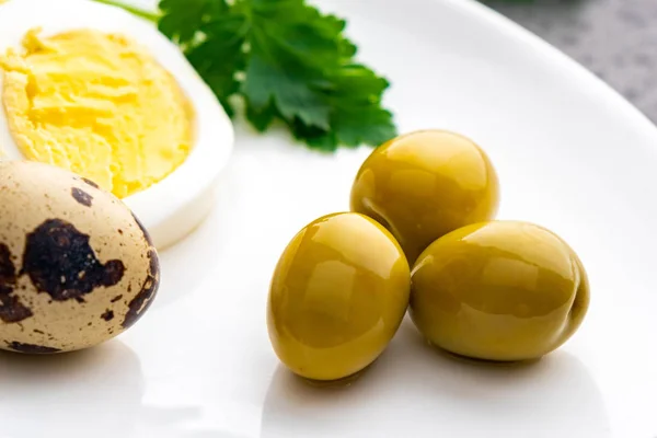 Boiled chicken eggs with quail eggs, olive and parsley on the wh — Stock Photo, Image