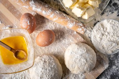 Pişirme tahtasında yumurta, tereyağı ve hamur ile beyaz un