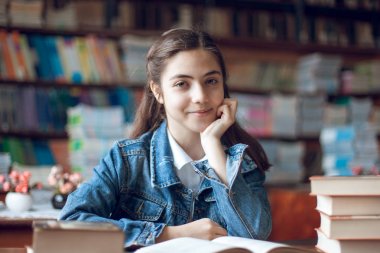 güzel kız öğrenci kütüphanede oturan ve bir kitap okuma