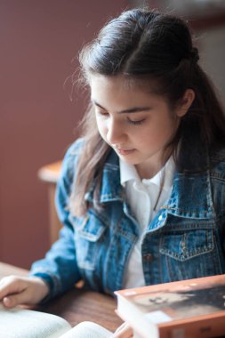 güzel kız öğrenci kütüphanede oturan ve bir kitap okuma