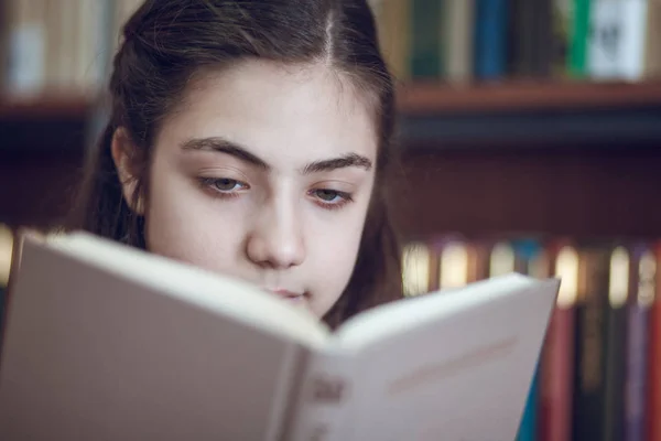 Bela estudante na biblioteca lendo um livro — Fotografia de Stock