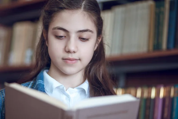 Piękna uczennica w bibliotece czytając książkę — Zdjęcie stockowe