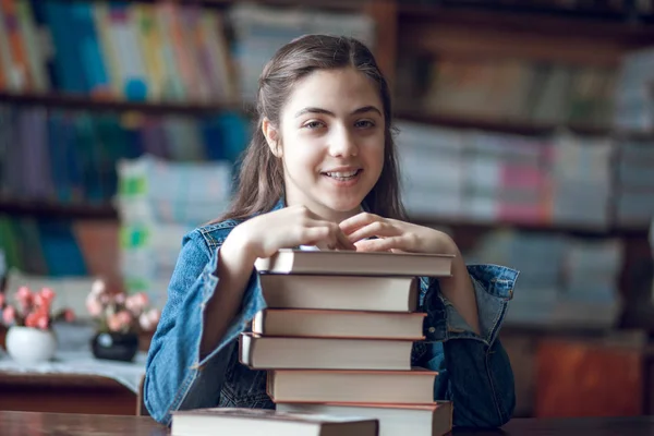 Bela estudante sentada na biblioteca com livros — Fotografia de Stock