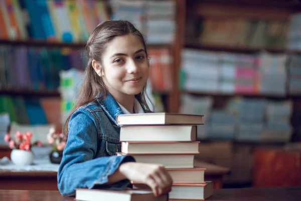 Bela estudante sentada na biblioteca com livros — Fotografia de Stock