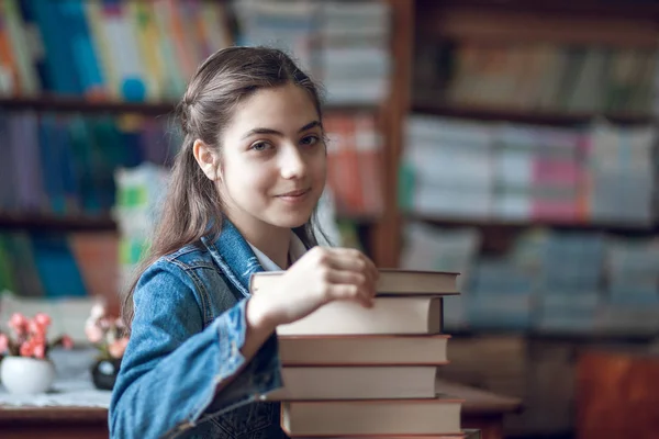 Bela estudante sentada na biblioteca com livros — Fotografia de Stock