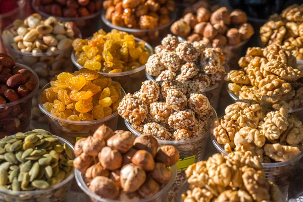 Una variedad de nueces en cuencos de plástico en el mercado al aire libre —  Fotos de Stock