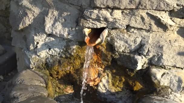 Vue rapprochée d'une fontaine à eau. Eau provenant d'un trou sur le mur recouvert d'algues. Svetitskhoveli, Mtskheta .