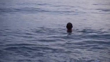 Kvariati sahilinde denizde yüzen adam. Gürcistan.