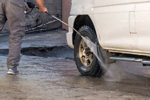 Un disparo de un hombre lavando su coche bajo agua de alta presión al aire libre — Foto de Stock