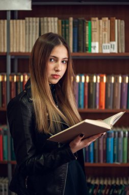 Kütüphanede bir kitap okuyan güzel genç kız öğrenci