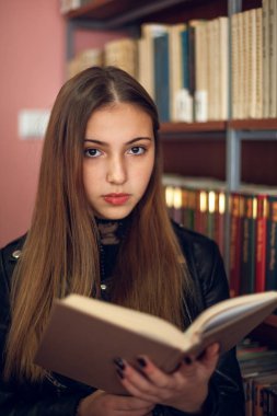 Kütüphanede bir kitap okuyan güzel genç kız öğrenci