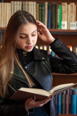 Kütüphanede bir kitap okuyan güzel genç kız öğrenci