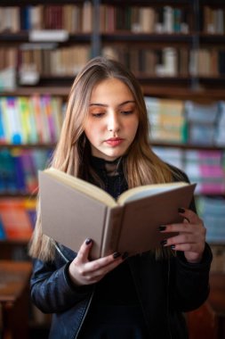 Kütüphanede bir kitap okuyan güzel genç kız öğrenci