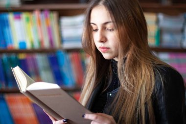 Kütüphanede bir kitap okuyan güzel genç kız öğrenci