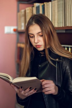 Kütüphanede bir kitap okuyan güzel genç kız öğrenci