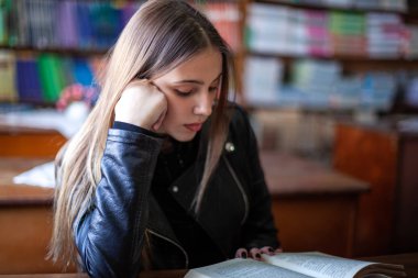 Güzel genç kız öğrenci kütüphanede oturan ve okuma