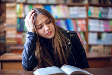 Güzel genç kız öğrenci kütüphanede oturan ve okuma