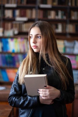 Kütüphanede bir kitap okuyan güzel genç kız öğrenci