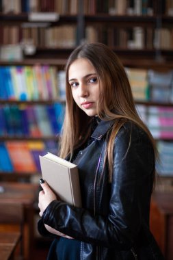 Kütüphanede bir kitap okuyan güzel genç kız öğrenci