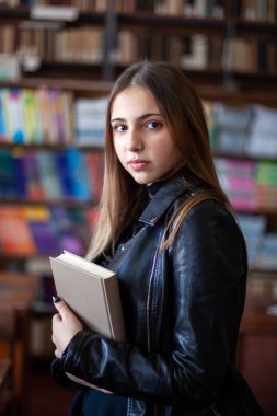 Kütüphanede bir kitap okuyan güzel genç kız öğrenci