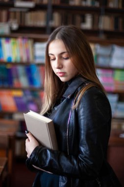 Kütüphanede bir kitap okuyan güzel genç kız öğrenci