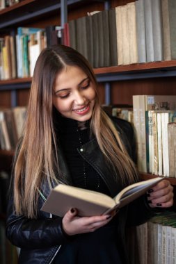 Kütüphanede bir kitap okuyan güzel genç kız öğrenci