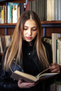 Kütüphanede bir kitap okuyan güzel genç kız öğrenci