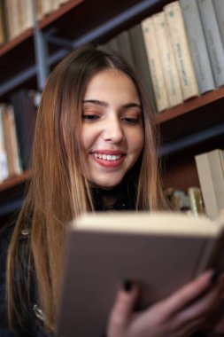 Kütüphanede bir kitap okuyan güzel genç kız öğrenci