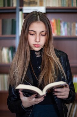 Kütüphanede bir kitap okuyan güzel genç kız öğrenci