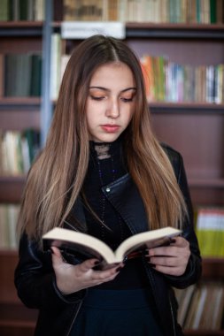 Kütüphanede bir kitap okuyan güzel genç kız öğrenci