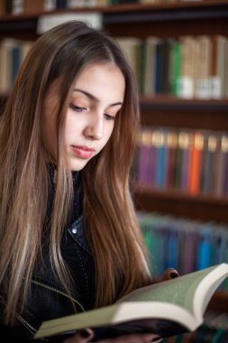 Kütüphanede bir kitap okuyan güzel genç kız öğrenci