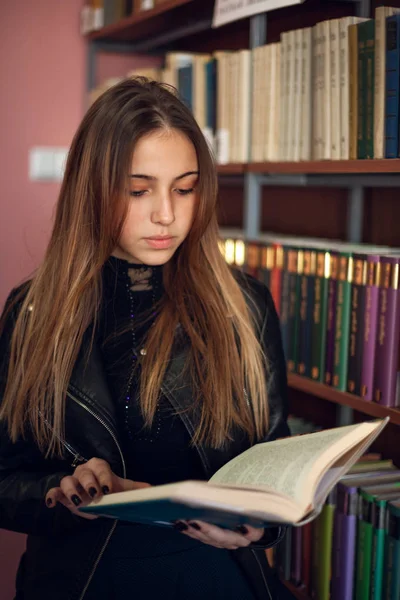 Bela adolescente estudante lendo um livro na biblioteca — Fotografia de Stock