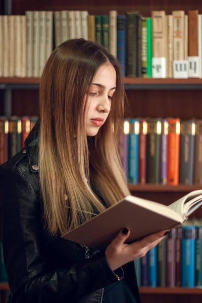 Belle écolière adolescente lisant un livre dans la bibliothèque — Photo