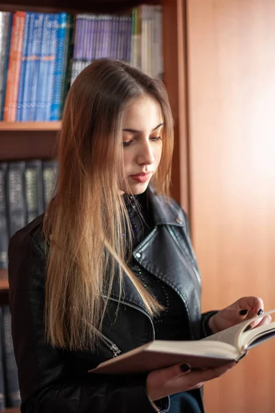 Hermosa adolescente colegiala leyendo un libro en la biblioteca — Foto de Stock