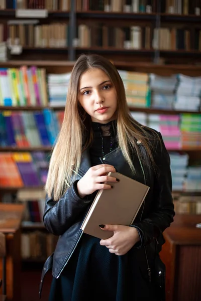 Beautiful teenager schoolgirl reading a book in the library — Stock Photo, Image