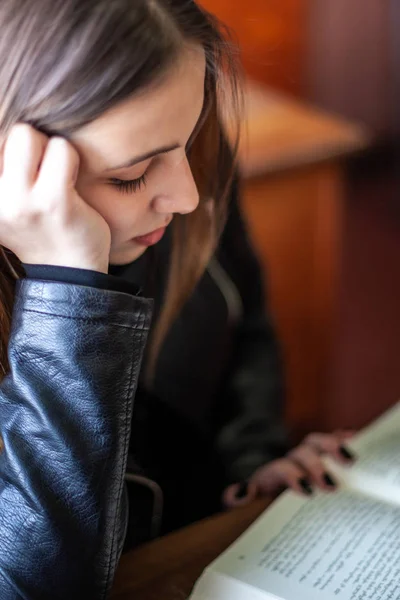 Hermosa adolescente colegiala sentada en la biblioteca y leyendo — Foto de Stock