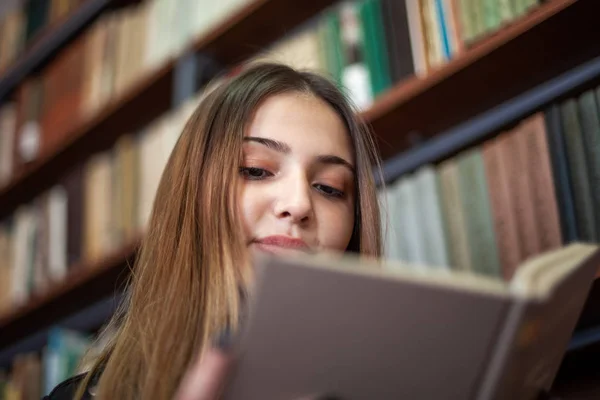 Belle écolière adolescente lisant un livre dans la bibliothèque — Photo