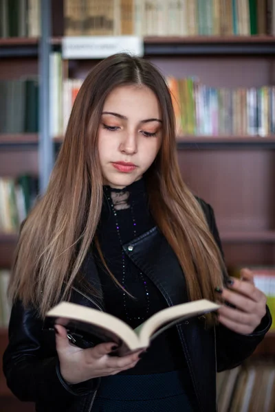 Bela adolescente estudante lendo um livro na biblioteca — Fotografia de Stock