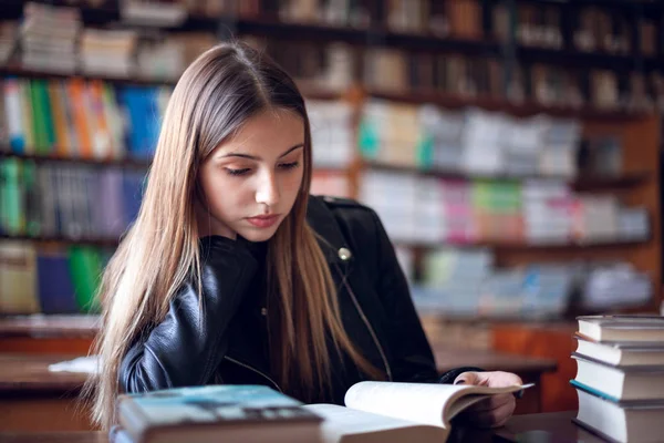 Belle écolière adolescente assise dans la bibliothèque et lisant — Photo