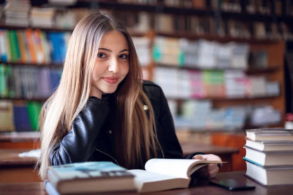 Bela adolescente estudante sentado na biblioteca e leitura — Fotografia de Stock