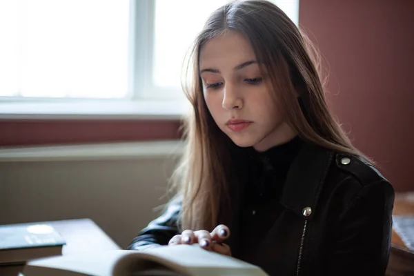 Güzel genç kız öğrenci kütüphanede oturan ve okuma — Stok fotoğraf