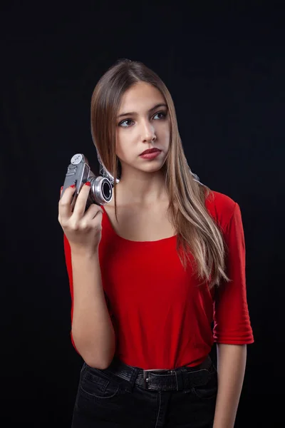 Menina bonita com câmera de estilo antigo posando em camisa vermelha no preto — Fotografia de Stock