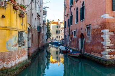 Venedik'te renkli tarihi evler arasında dar kanal üzerinde Tekneler